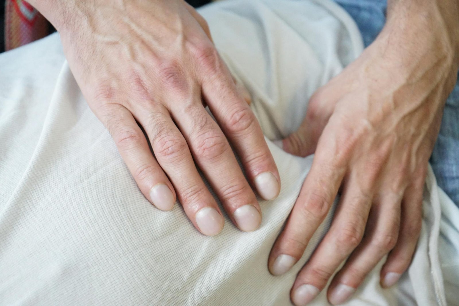 Detailed view of hands giving a soothing massage on a white fabric indoors. Perfect for wellness themes.